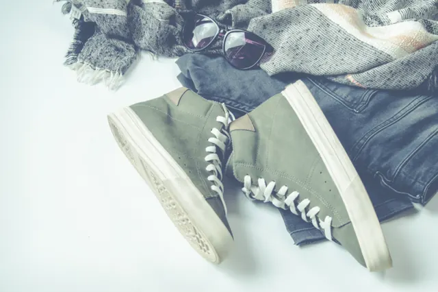 Canvas sneakers next to jeans and a scarf